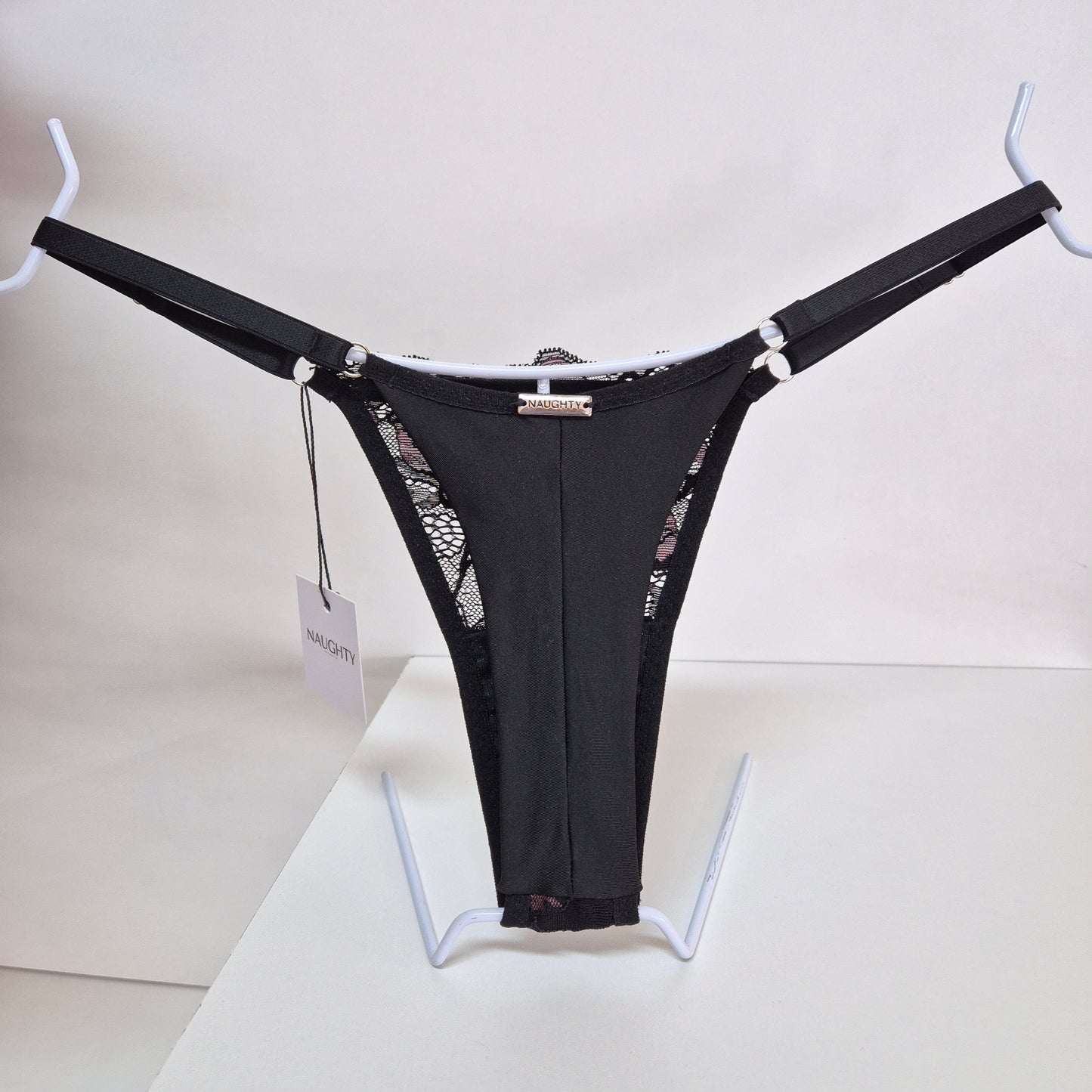 Calcinha string Seduce preta com detalhes em renda e flor bordô, alças ajustáveis e design sensual. Fio duplo em microfibra e plaquinha personalizada na cor prata.