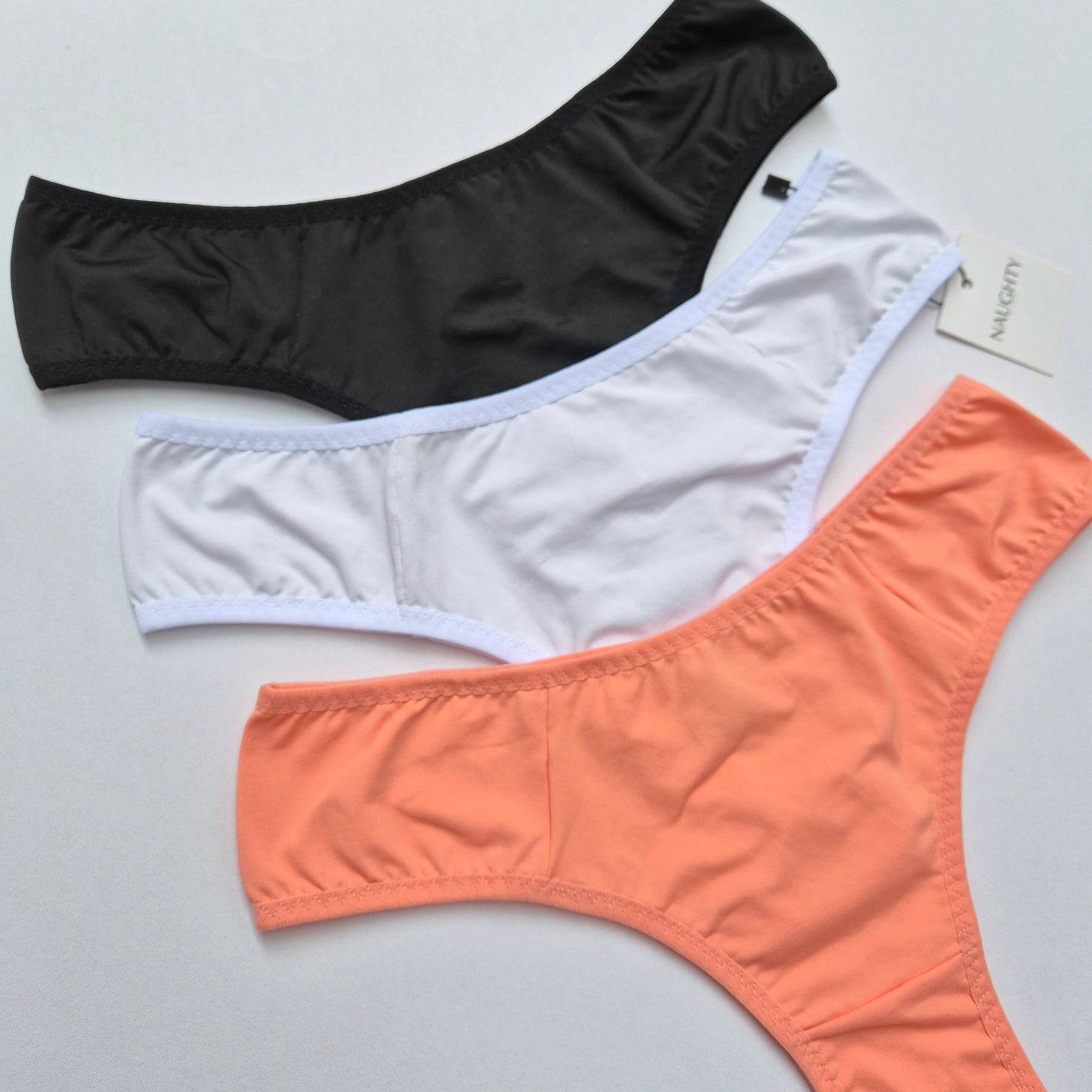 Kit de calcinhas básicas nas cores preta, branca e coral, modelagem confortável e toque suave. Calcinha toda em microfibra e forro 100 algodão. Plaquinha personalizada naughty na cor prata. 