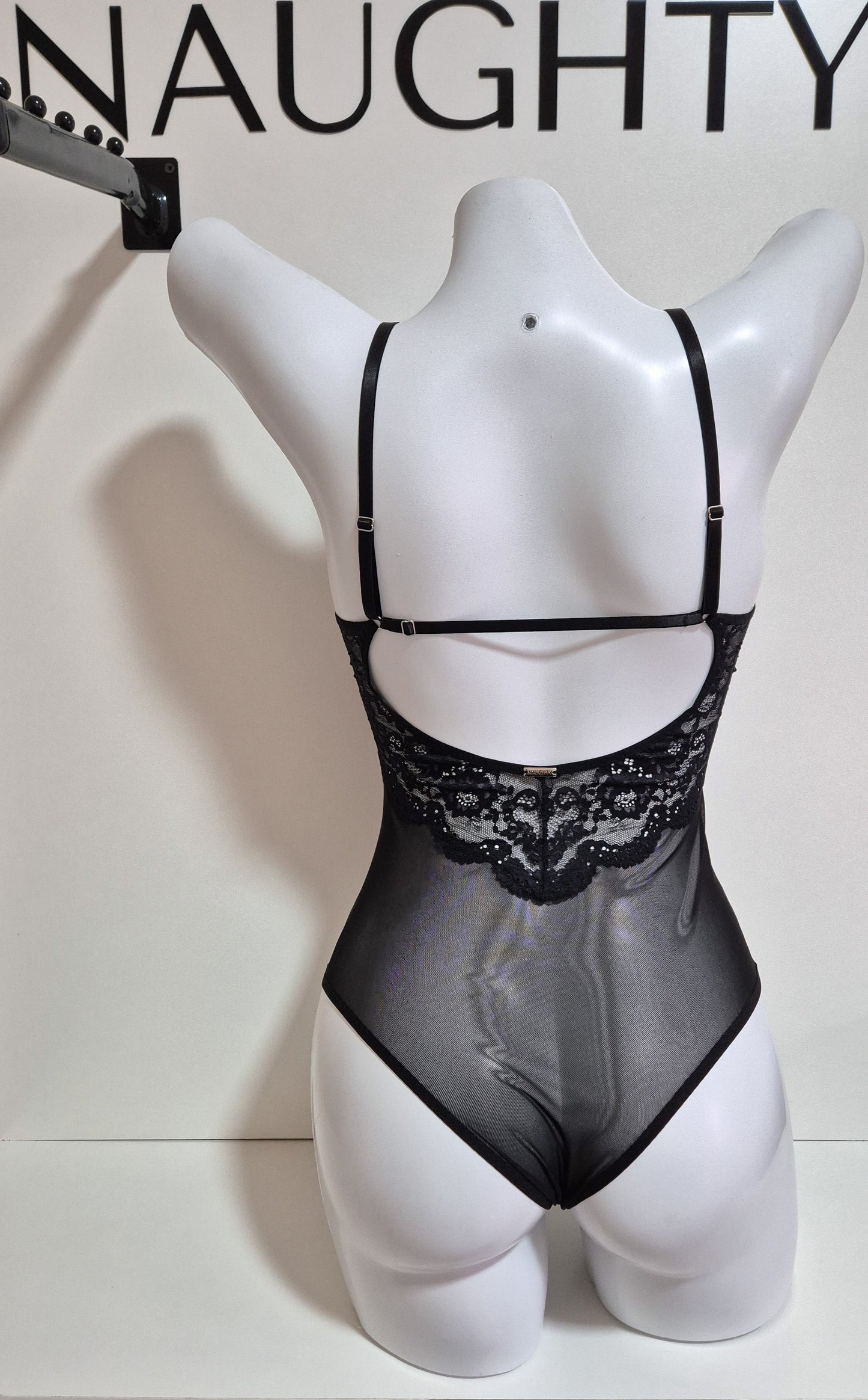 Body Luna preto no manequim em renda delicada com decote em V profundo, acabamento artesanal e femininos. Costas com renda e ajustável. Plaquinha em prata com a logo da marca.