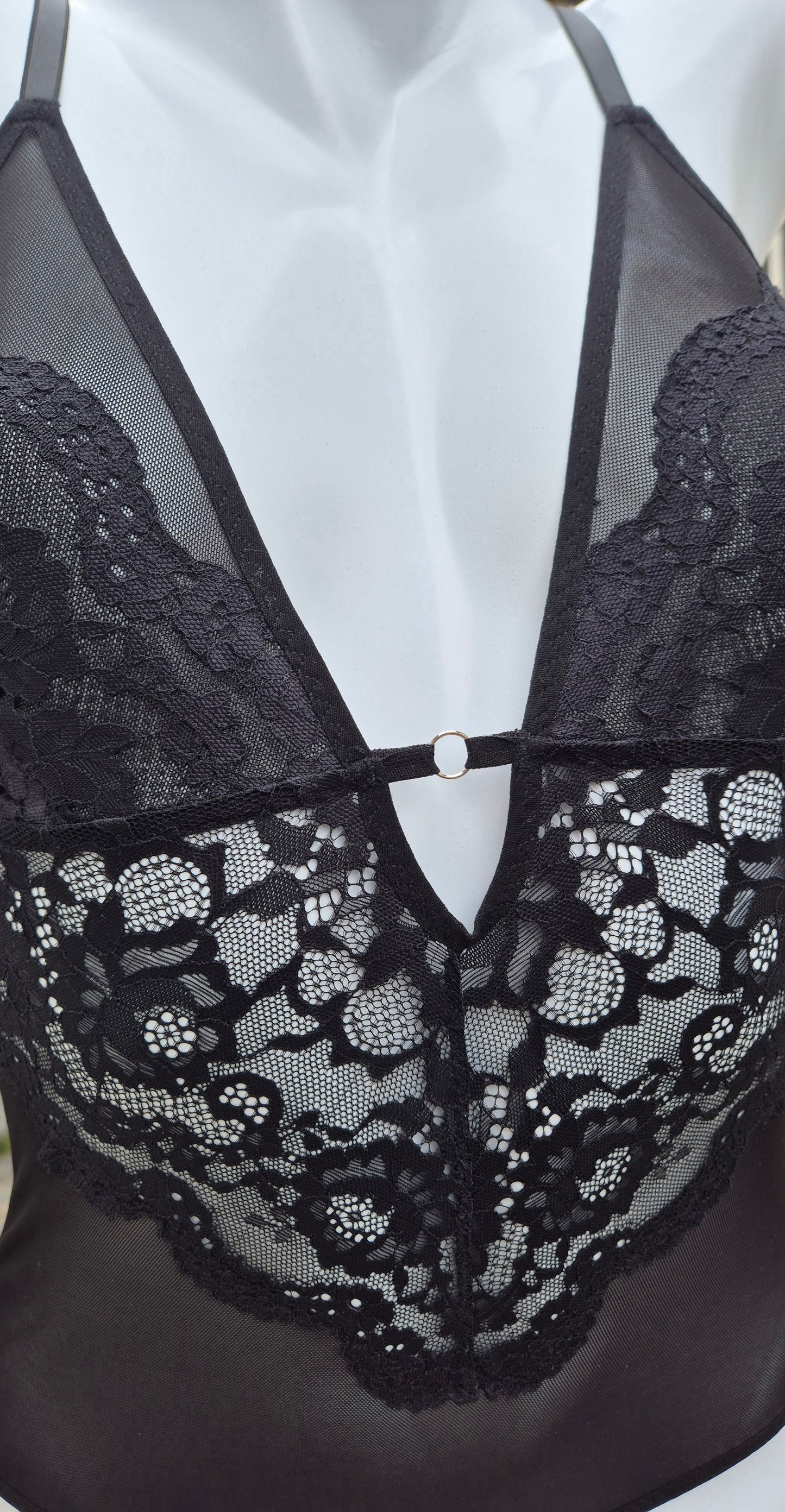 Body Luna preto em renda delicada com decote em V profundo, acabamento artesanal e detalhes femininos. Argola no decote na cor prata e plaquinha personalizada da marca em prata. 