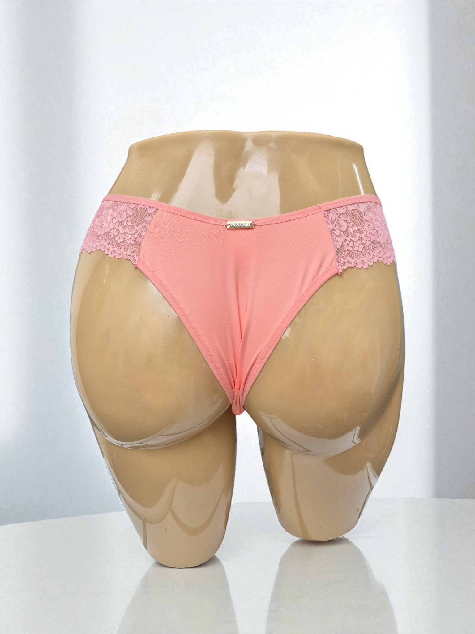 Calcinha Belle coral com laterais em renda delicada, cintura média, modelagem confortável e plaquinha dourada Naughty. Frente e costas em microfibra, forro 100% algodão. Peça artesanal