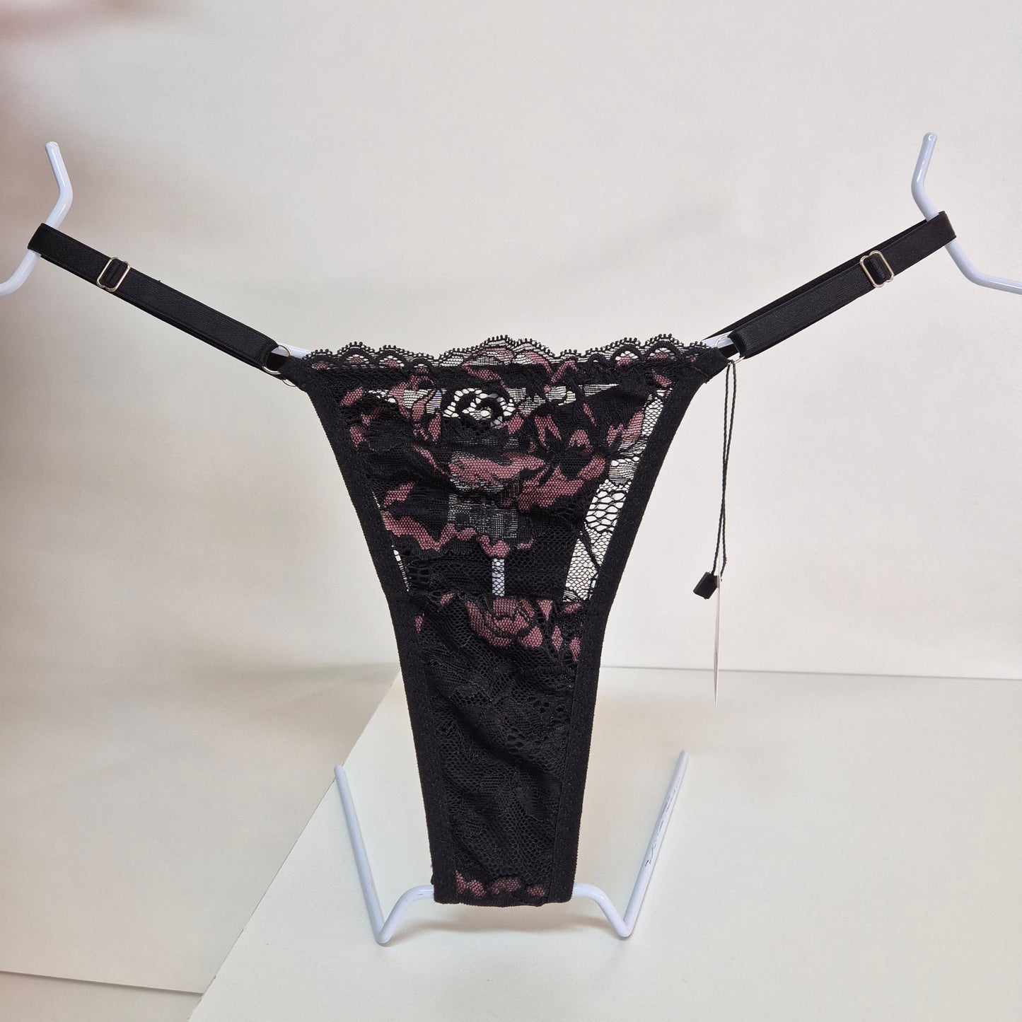 Calcinha string Seduce preta com detalhes em renda e flor bordô, alças ajustáveis e design sensual. Fio duplo em microfibra e plaquinha personalizada na cor prata. 