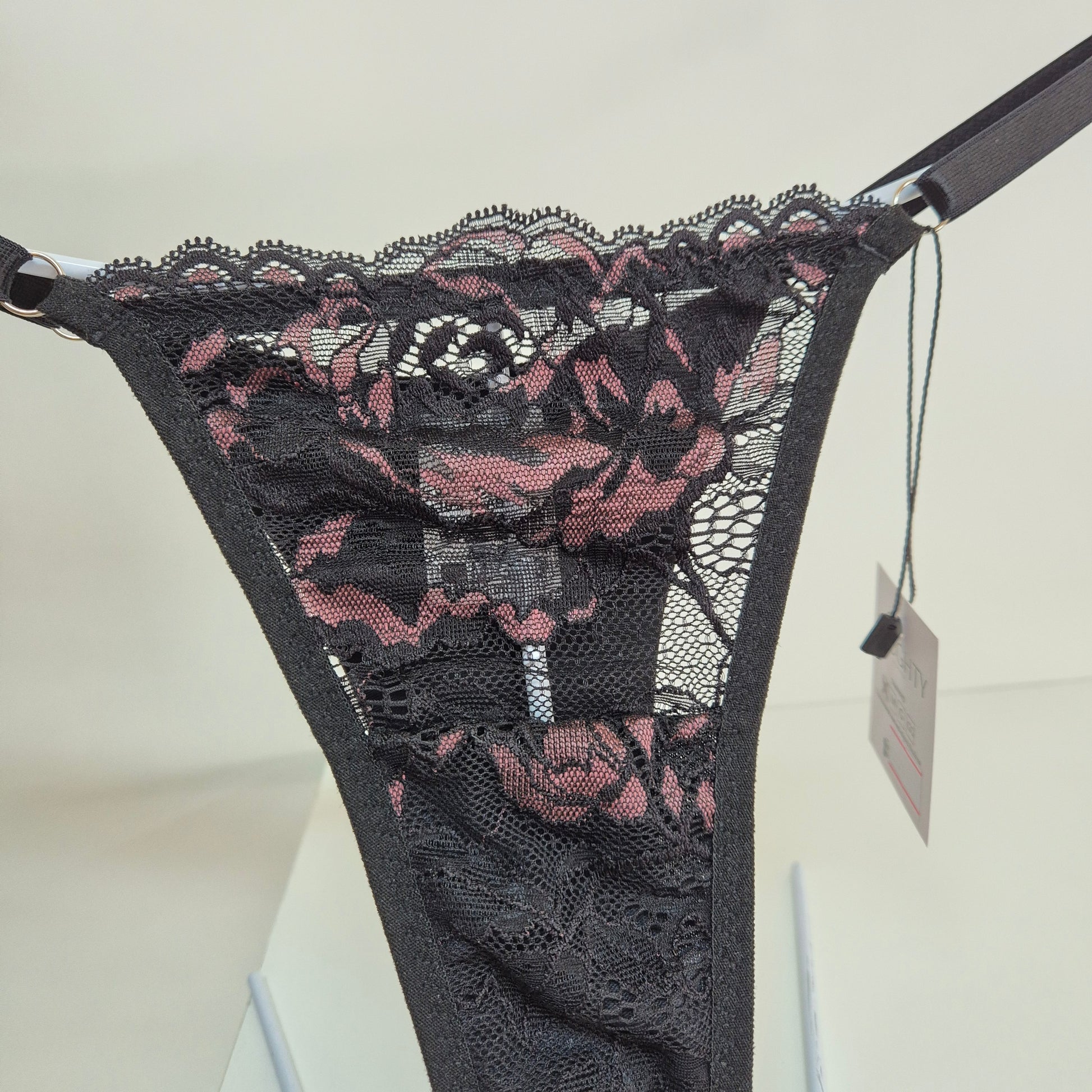Calcinha string Seduce preta com detalhes em renda e flor bordô, alças ajustáveis e design sensual. Fio duplo em microfibra e plaquinha personalizada na cor prata. 