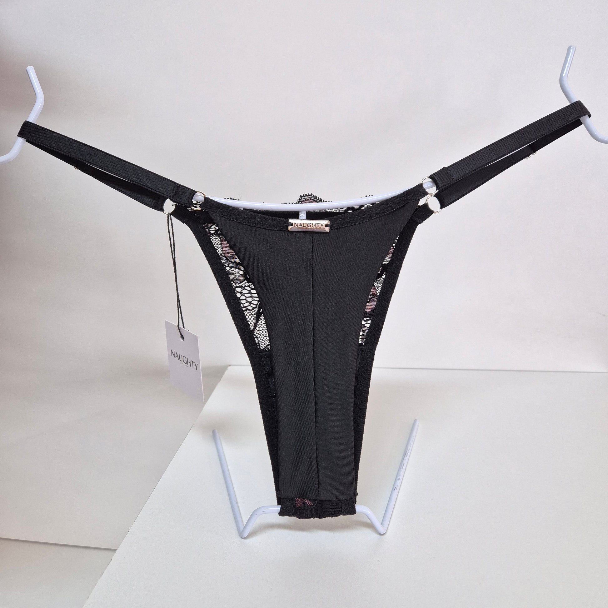 Calcinha string Seduce preta com detalhes em renda e flor bordô, alças ajustáveis e design sensual. Fio duplo em microfibra e plaquinha personalizada na cor prata. 